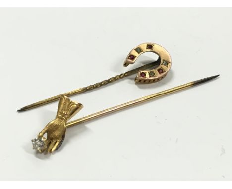 A yellow metal stick pin brooch decorated with a lover's hand holding a diamond together with another mounted with a horsesho