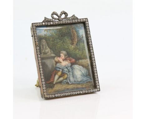 Erotic portrait miniature depicting a man and woman leaning against a wall, in paste set frame with bow surmount, 8.5cm x 6.5