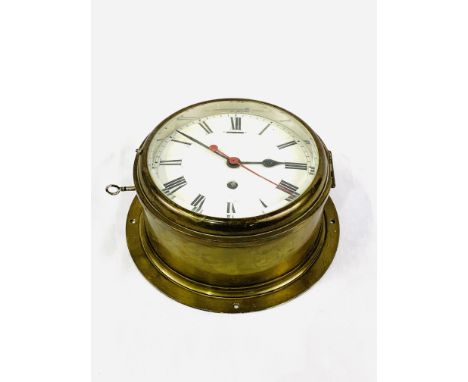 Large brass cased bulkhead clock, with key to case, diameter 22cms. Estimate £30-50