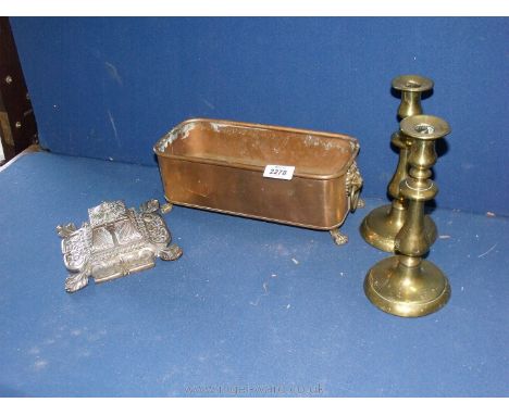 A copper planter with a pair of brass candlesticks and an ornate brass inkwell with ceramic well.
