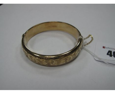 A 9ct Gold Bangle, leaf scroll engraved to the front, hinged to snap clasp. 