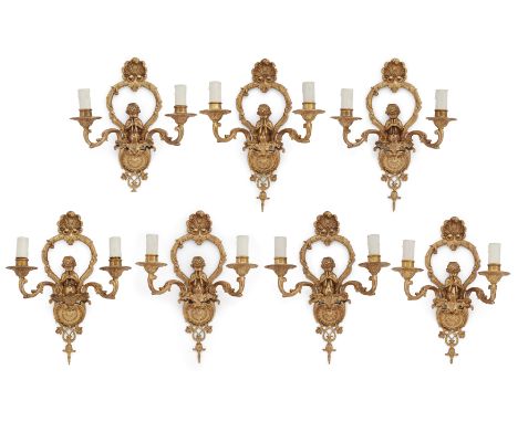 Seven French gilt-bronze twin-light wall appliques, 20th century, in the manner of Jean Hauré, the backplates modelled with a