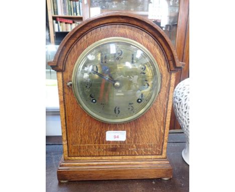 AN EDWARDIAN OAK-CASED MANTLE CLOCK with brass dial