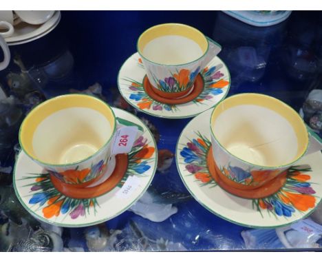 CLARICE CLIFF; THREE CROCUS CUPS AND SAUCERS with Art Deco handles (one cup broken)