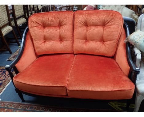 A REPRODUCTION TWO SEATER SOFA with an ebonised frame and bright orange velvet upholstery, 130cm wide