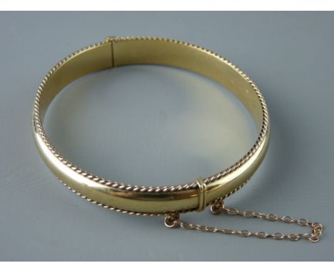 A NINE CARAT CLOGAU GOLD BANGLE with gadrooned edging and safety chain in original box, 13 grms 