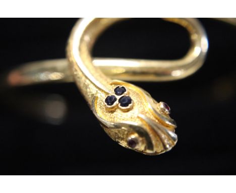 A solid 18ct gold bangle in the form of a serpent. With sapphire &amp; rubies. 16.84 grams. 