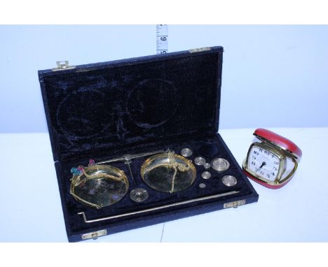 A vintage travel alarm clock and a cased set of brass weighing scales 