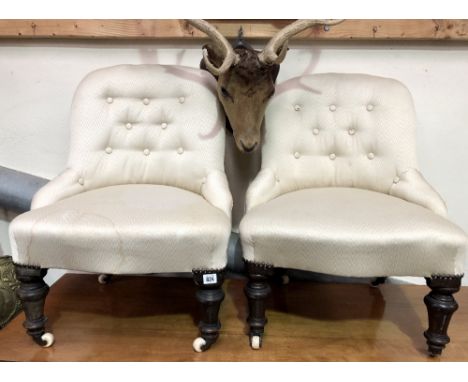 Pair of Victorian button back upholstered nursing chairs with turned forelegs and brass caps with ceramic castors.