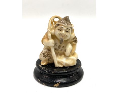 Japanese porcelain simulating ivory figure of a fisherman upon ebonised stand, height of figure 4.5cm.