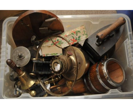 A box containing a quantity of oddments including a cast iron iron, a brass oil lamp and other metalware
