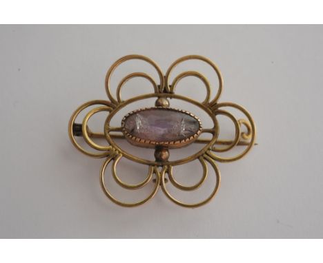 A yellow metal brooch set with central amethyst
