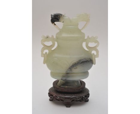 A Chinese carved green hard stone lidded vase, possibly jade, with traces of black impurities with free spinning loop handles