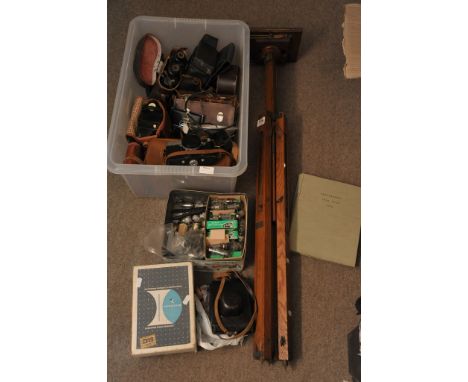 An old wooden camera tripod and box of various cameras and equipment
