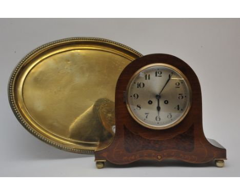 An inlaid mantle clock with key and pendulum and a brass tray