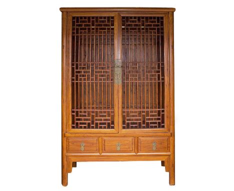 An Asian hardwood wardrobe, fitted with two pierced latticework doors, opening to reveal hanging space and single shelf, thre