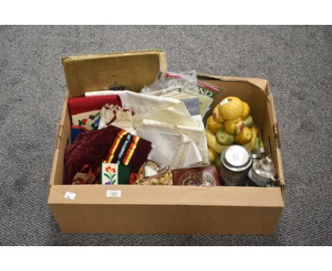 An eclectic collection of items including an assortment of embroidered table linen, a traditional embroidered baby's costume,