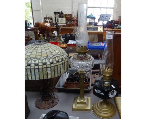 A Tiffany style table lamp with leaded glass shade, a Young's brass oil lamp with cut-glass font, and another oil lamp 