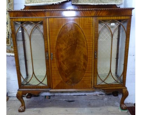 An 1930s mahogany breakfront bookcase, with 2 glazed and 1 panel door, on claw and ball feet, W137cm, H147cm 