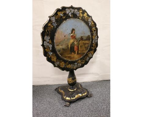 An Victorian lacquered tilt top table with central painted panel entitled "The Mothers Blessing", encircled by gilt floral sp