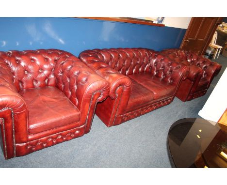 Ox blood red leather Chesterfield sofa and pair of matching tub chairs.