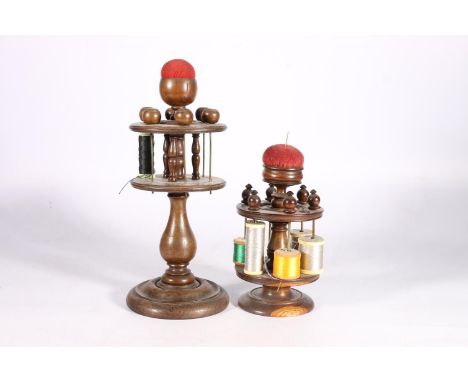 Two 19th century turned spool holders in oak, with pincushions to the central pillar, 20cm and 29cm. 