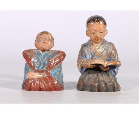 Two Japanese painted ceramic figures, one of a kneeling boy reading a book, the other of a seated figure with nodding head, T