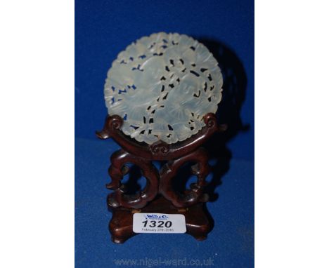 A carved Jade Disc, 3'' diameter, on wooden stand.  