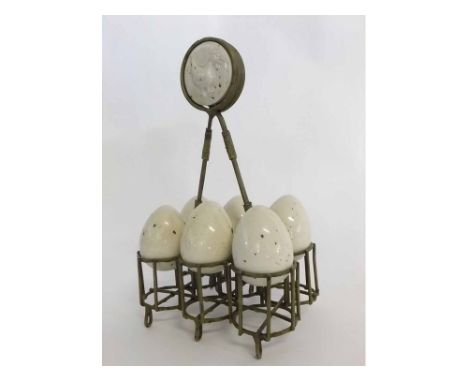 Metal egg cruet with glazed circular plaque and raised cockerel, with six white glazed  ceramic eggs, 23cms tall