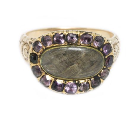 A Scottish(?) Georgian mourning ring, central oval panel of plaited hair behind an oval colourless paste cabochon, surrounded