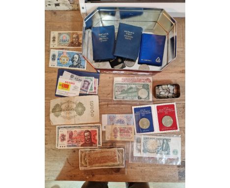 A tin of assorted Uk coins &amp; world banknotes to include a small tin of silver threepences &amp; coin sets etc.