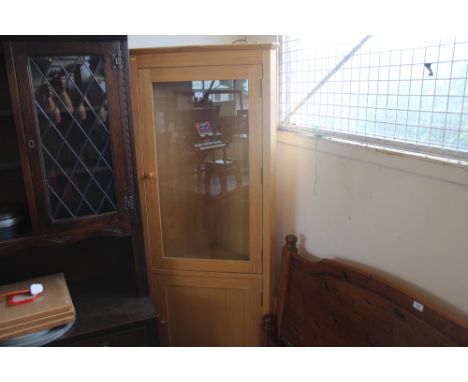 A light oak and glazed corner cabinet