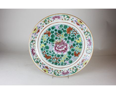 A Chinese famille rose porcelain charger decorated with a central peony and polychrome flowers and foliage in green circular 