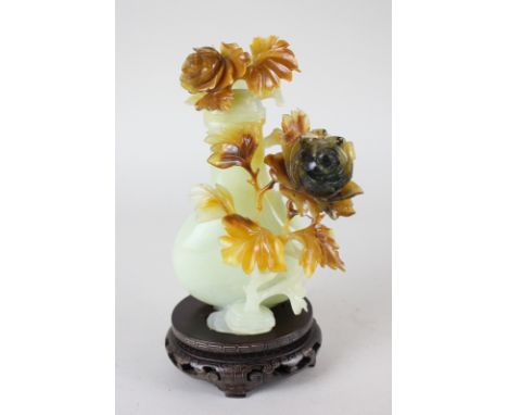 A Chinese carved and pierced jade jar and cover, the intricately carved floral design in contrasting colour, raised on a deco