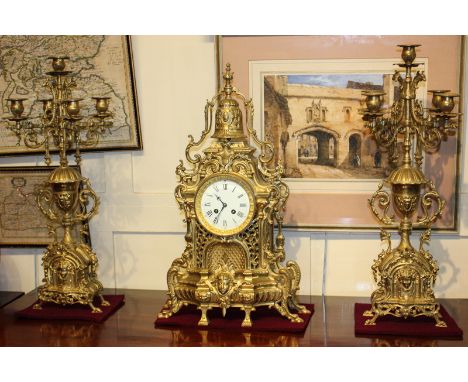 A reproduction Louis XVI style gilt metal clock garniture, a mantle clock and two five light candlesticks