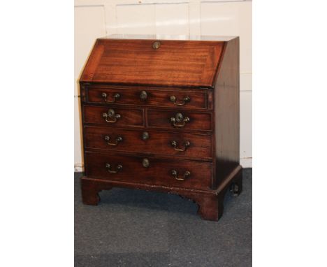A George III mahogany bureau with fitted interior of small drawers, pigeon holes and well, above dummy drawer, two short and 