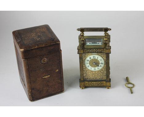 A gilt brass and  bevelled glass cased carriage clock, the circular enamel dial with Arabic numerals and gilt scrolling, foli