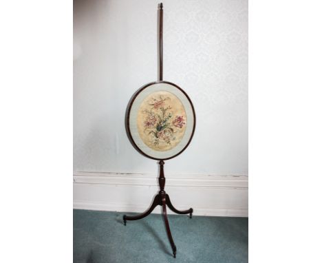 A George III mahogany pole fire screen with oval silk embroidered floral and glazed panel, an adjustable pole, on slender spl