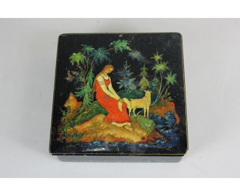 A Russian black lacquer square trinket box, the lid depicting a young woman seated in a forest with a goat,  signed and dated