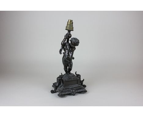 A bronzed spelter table lamp of a putti holding aloft a light, on scroll decorated base, 30cm