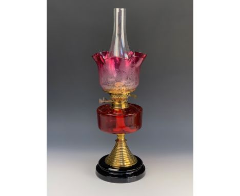 A Victorian oil lamp, having a cranberry glass reservoir and etched achromatising shade, 43 cm to top of shade