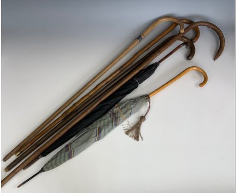 A group of vintage walking canes and two umbrellas