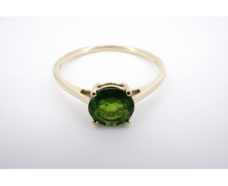 A contemporary 9ct gold and precious green gemstone dress ring, having a central round-cut gemstone of approximately 7 mm, in