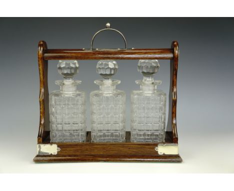 A late 19th / early 20th Century electroplate-mounted oak three-decanter tantalus