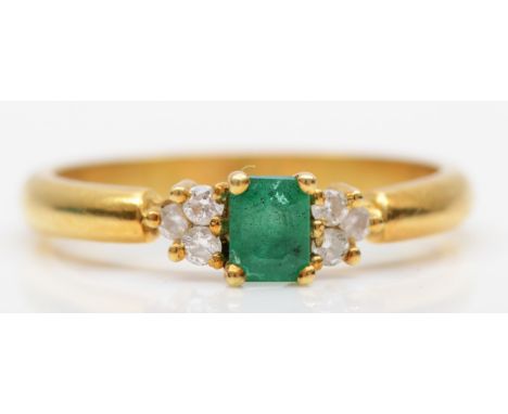 An 18ct gold emerald and diamond ring, claw set with an emerald cut stone flanked by brilliant cut trefoil shoulders, N, 3.4g