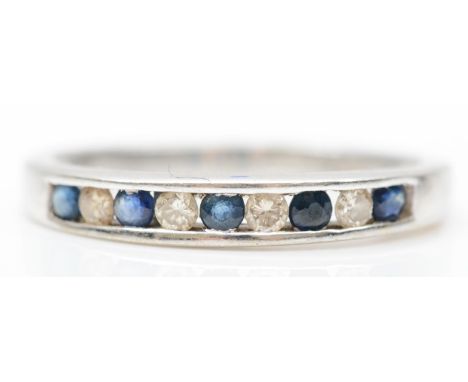 A 9ct white gold sapphire and diamond nine stone ring, channel set with brilliant cut stones, stated weight 0.15cts, O, 2.1gm