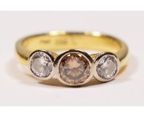 An 18ct gold three stone brilliant cut diamond ring, collet set with a champagne stone, estimated to weigh 0.50cts, flanked b