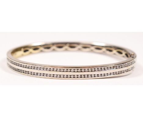 An 18ct white gold and brilliant cut diamond hinged bangle, channel set with two rows of fifty stones, total weight estimated