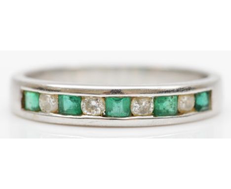 A 14K white gold, emerald and diamond nine stone ring, channel set with brilliant cut stones, O, 2.8gm 