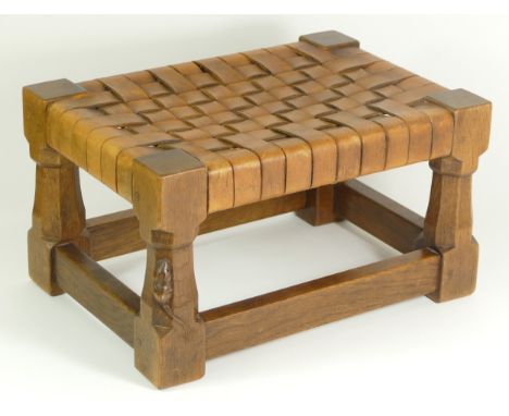 A Robert 'Mouseman' Thompson footstool, having cowhide interwoven strap top, supported by carved octagonal oak legs, one with